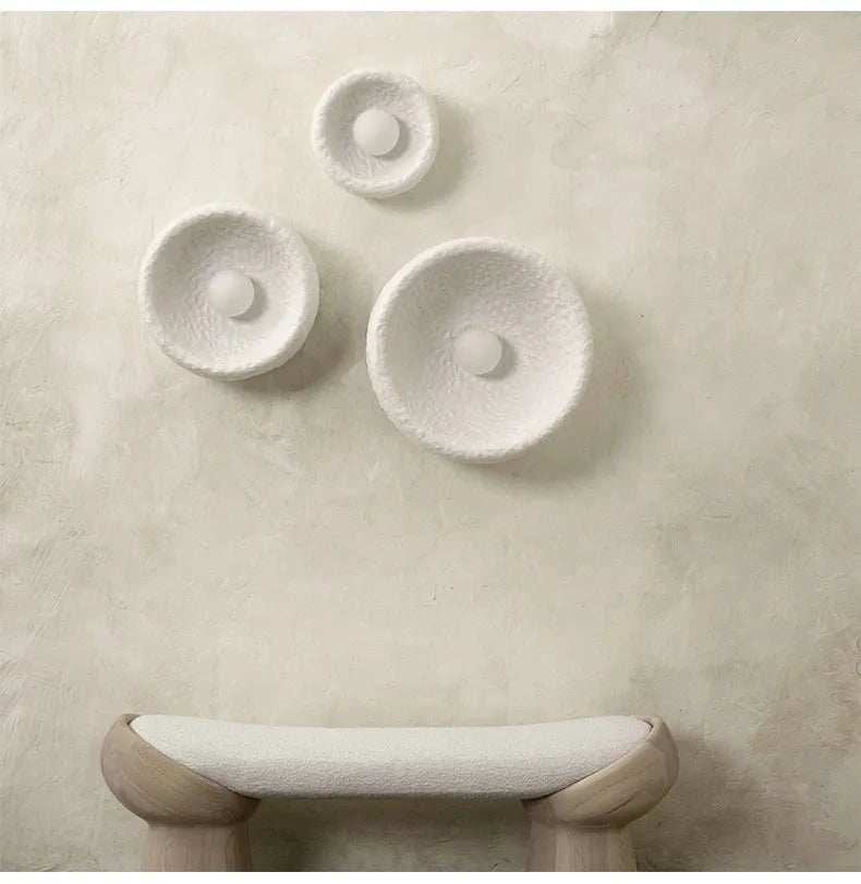 Japanese-style simple white resin wall lamp emitting warm light on a plain wall.