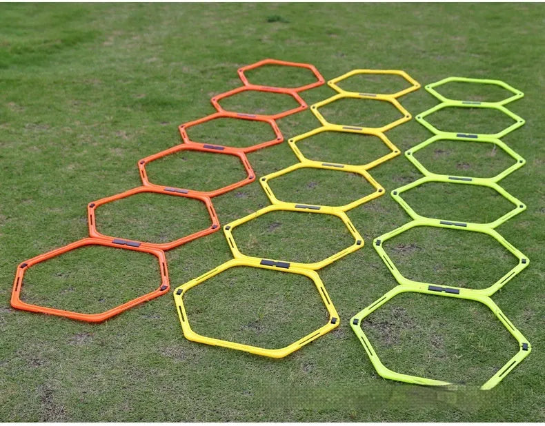 Set of six foldable yellow hexagon plastic agility training rings laid out on grass.