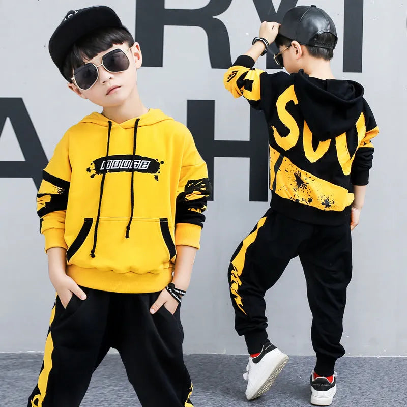 Boy's black and yellow hooded cotton sports suit trousers set on hanger, showing Korean style letter pattern.