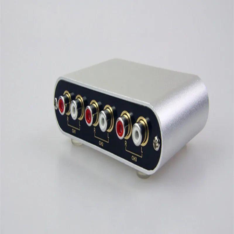 Silver aluminium alloy audio source switcher unit with front-panel switch button and infrared remote control.