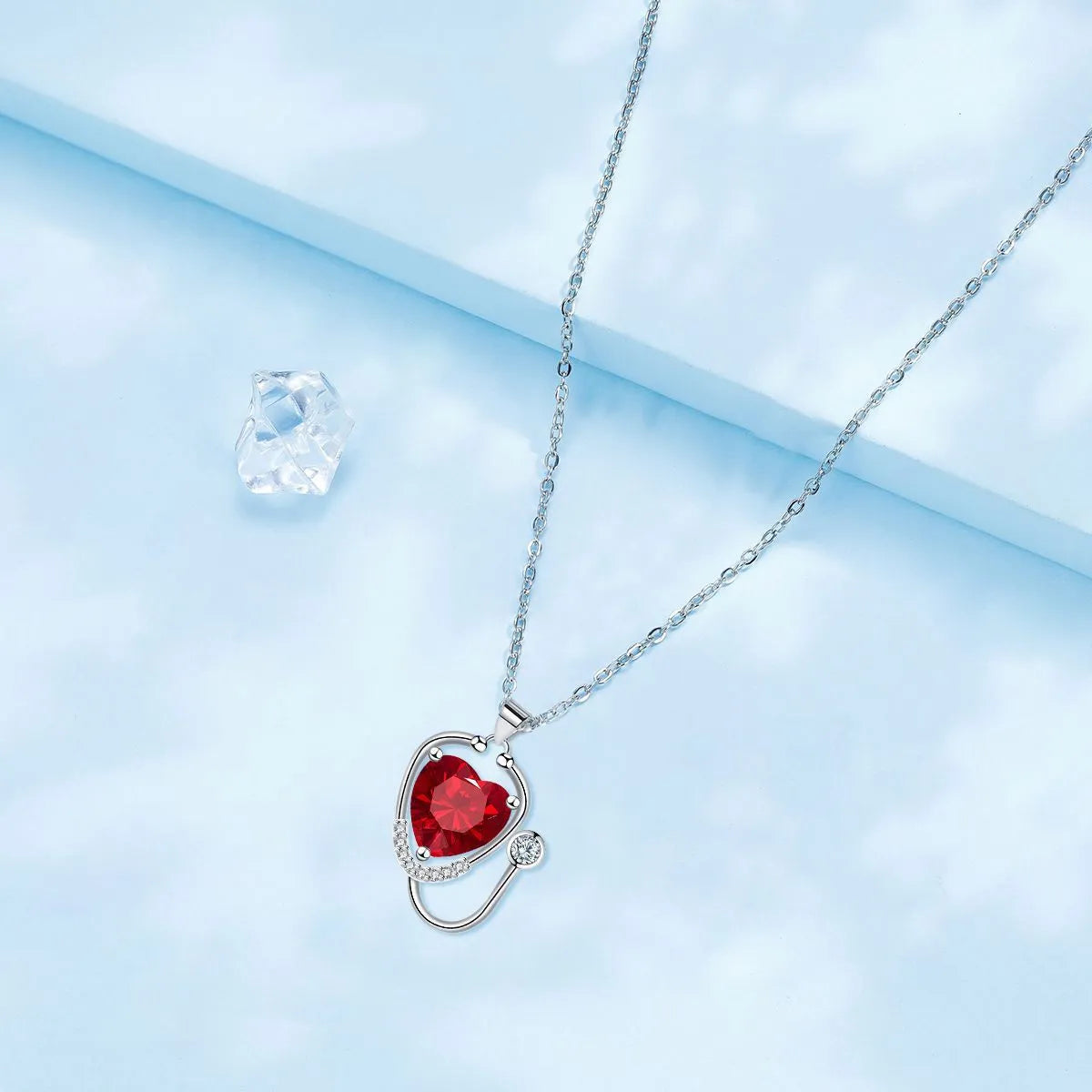 Close-up of a women's copper necklace with a red diamond wings cross stethoscope pendant.