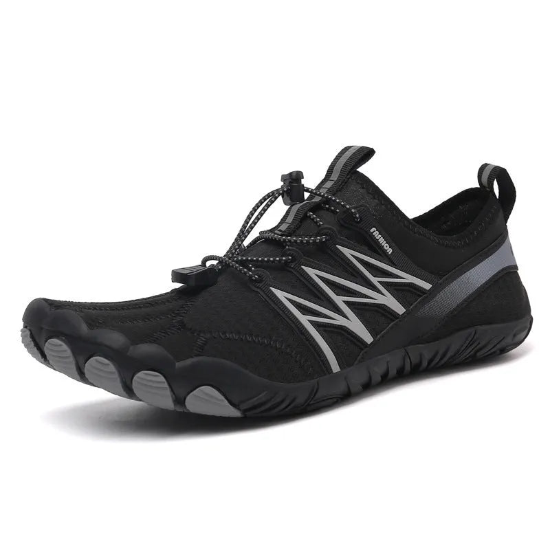 Low-top black and grey indoor training sneakers with mesh upper and rubber sole on a gym floor.