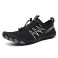 Low-top black and grey indoor training sneakers with mesh upper and rubber sole on a gym floor.