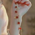 Close-up of a double-layer women's bracelet with a red agate blessing card and a red horse charm on an alloy band.