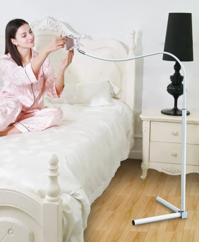 Black bedside mobile phone bracket with universal clamp mounted on a bed frame.