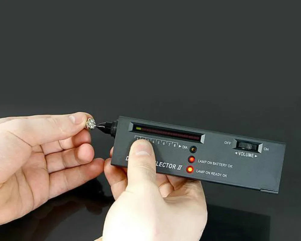 Black handheld diamond thermal conductivity tester with metal probe on a grey background.