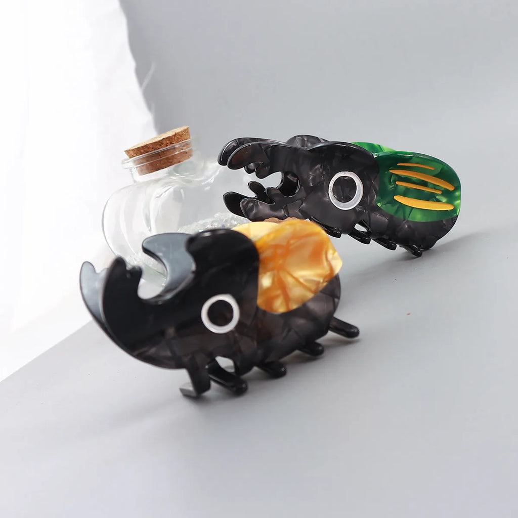 Handmade cartoon insect design hair grip in green beetle, orange beetle, or white caterpillar colour on cellulose acetate.