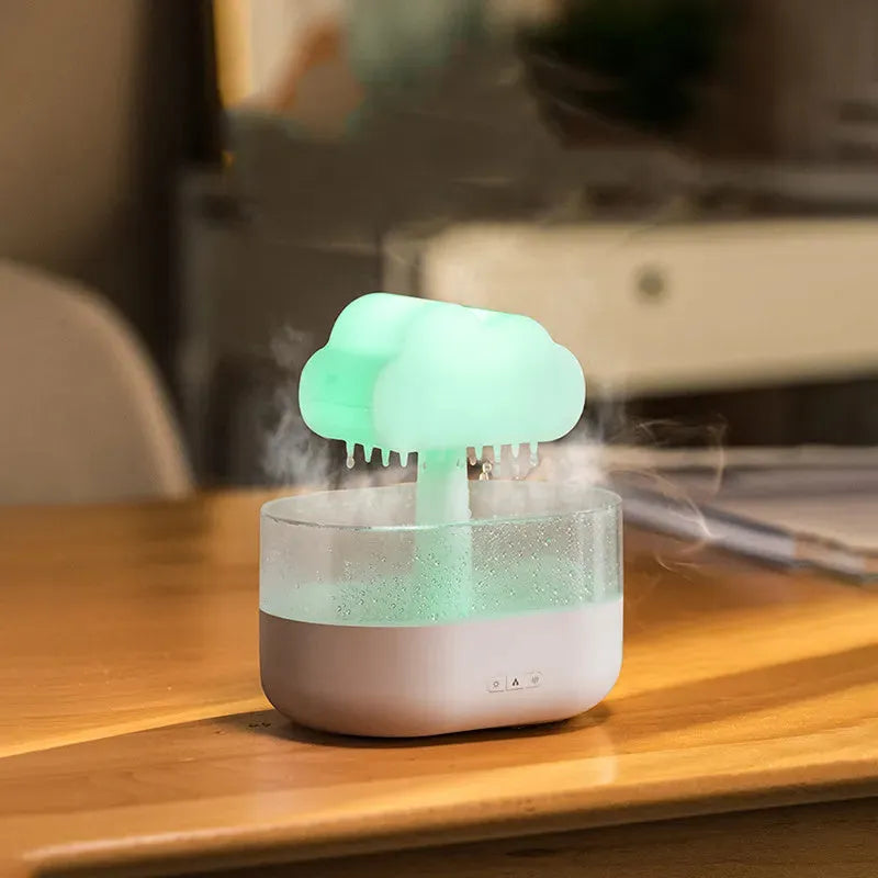 White cloud-shaped humidifier diffuser with multi-colour LED lights on a wooden surface.