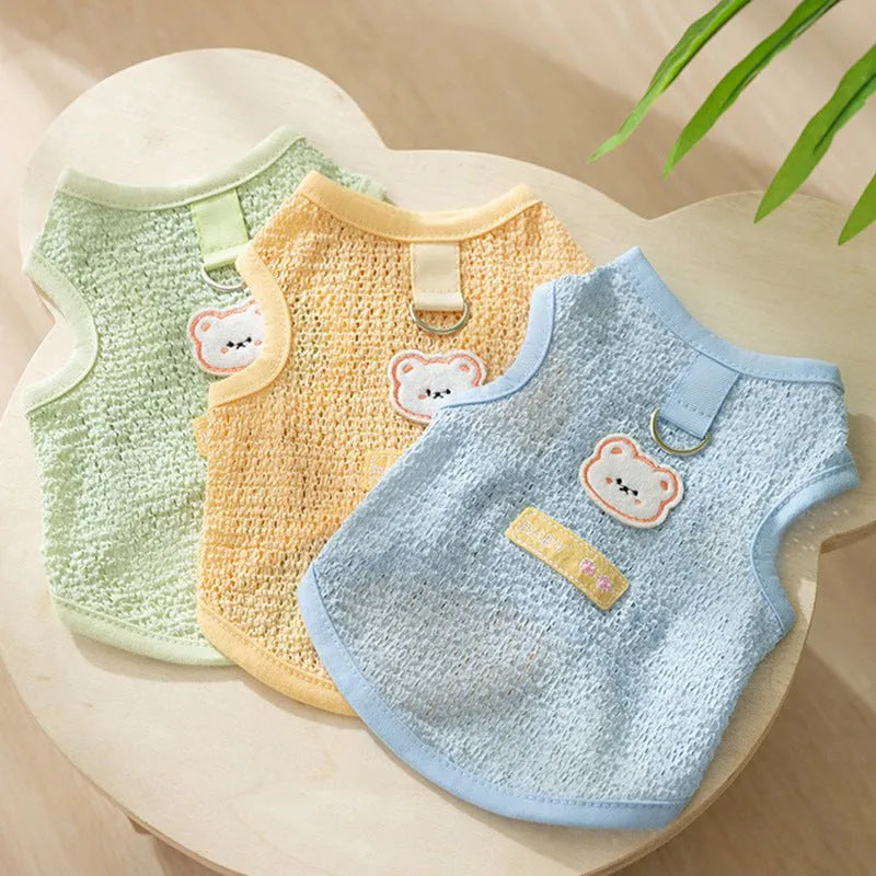 Cat wearing green knitted clothes with a bear patch, showing breathable hollowed-out fabric design.