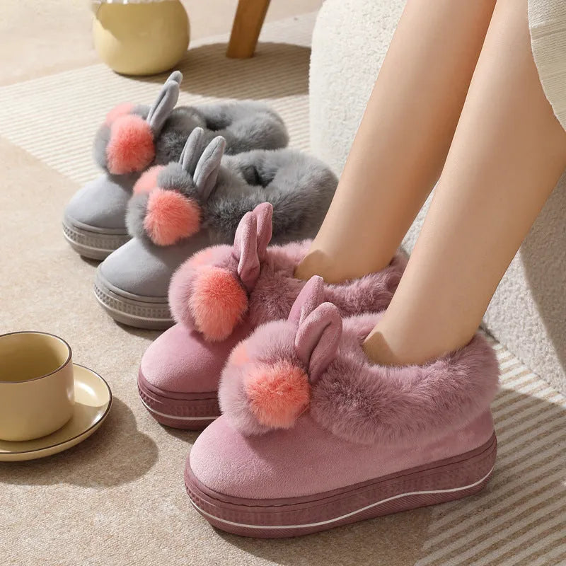 A pair of grey high heel winter slippers with a thick sole and plush upper, shown on a white background.