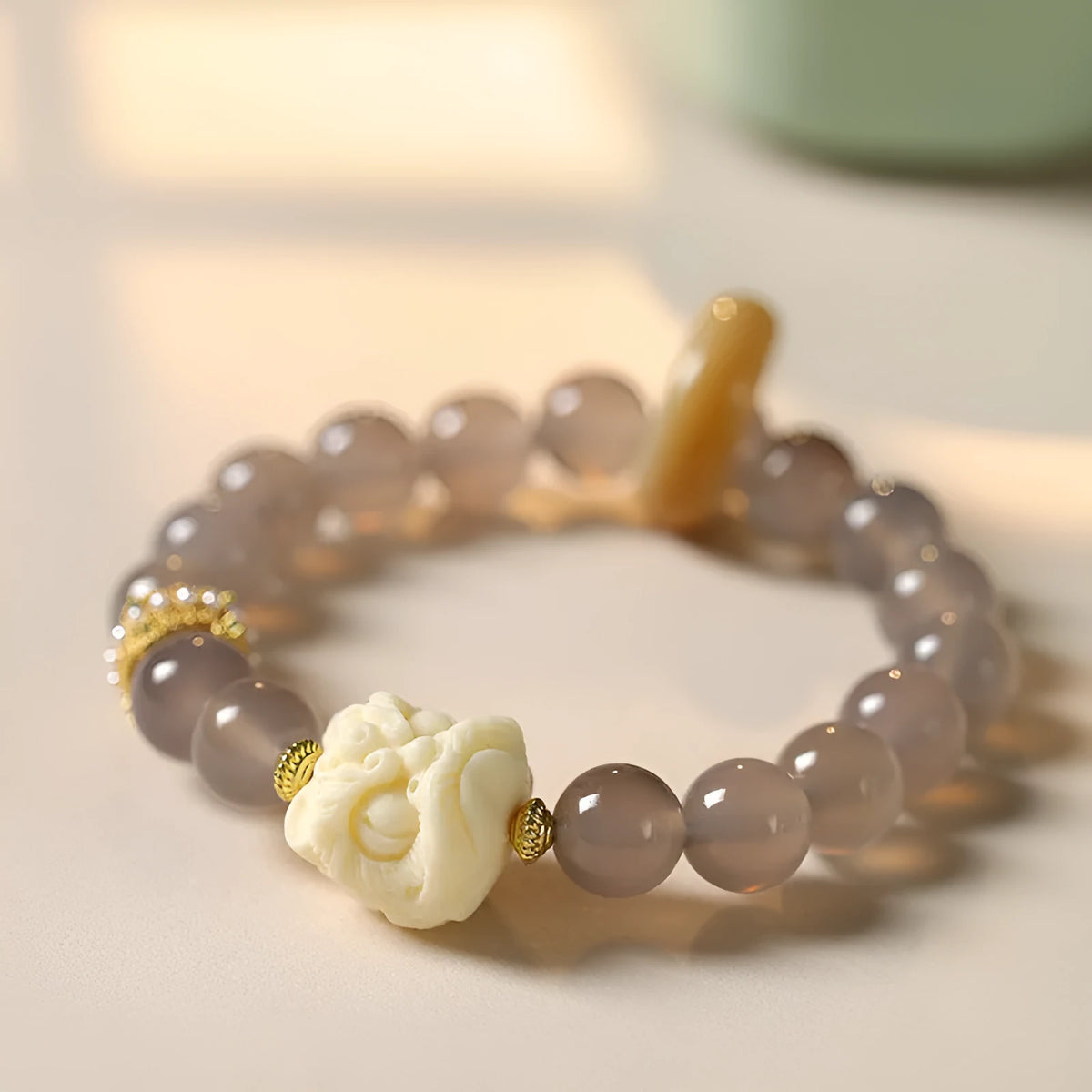 Hand-woven bracelet with round grey agate and mellite beads on a white background.