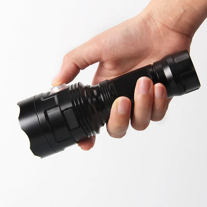 Black aluminium XHP90 LED tactical flashlight showing its size next to a USB charging cable.