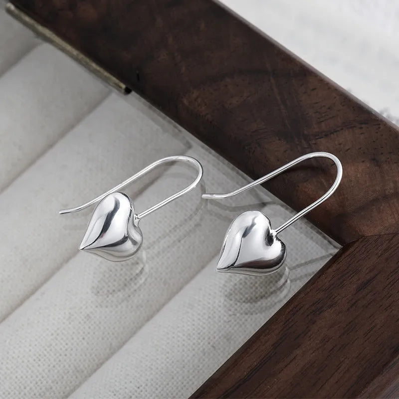 Heart-shaped copper earrings with white gold plating and glossy finish, showing three-dimensional design