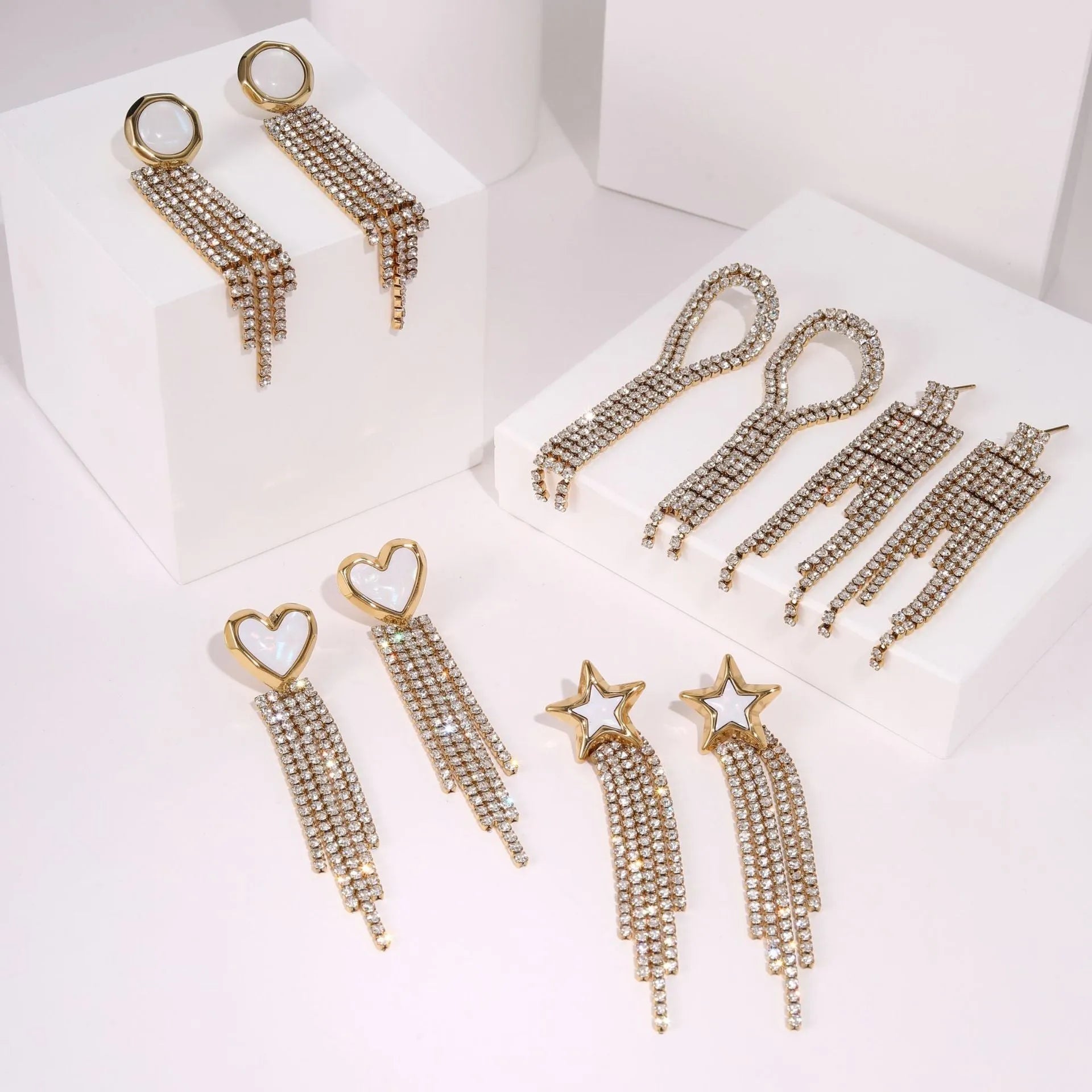 Gold-colour stainless steel earrings with heart and star tassel designs on a white background.