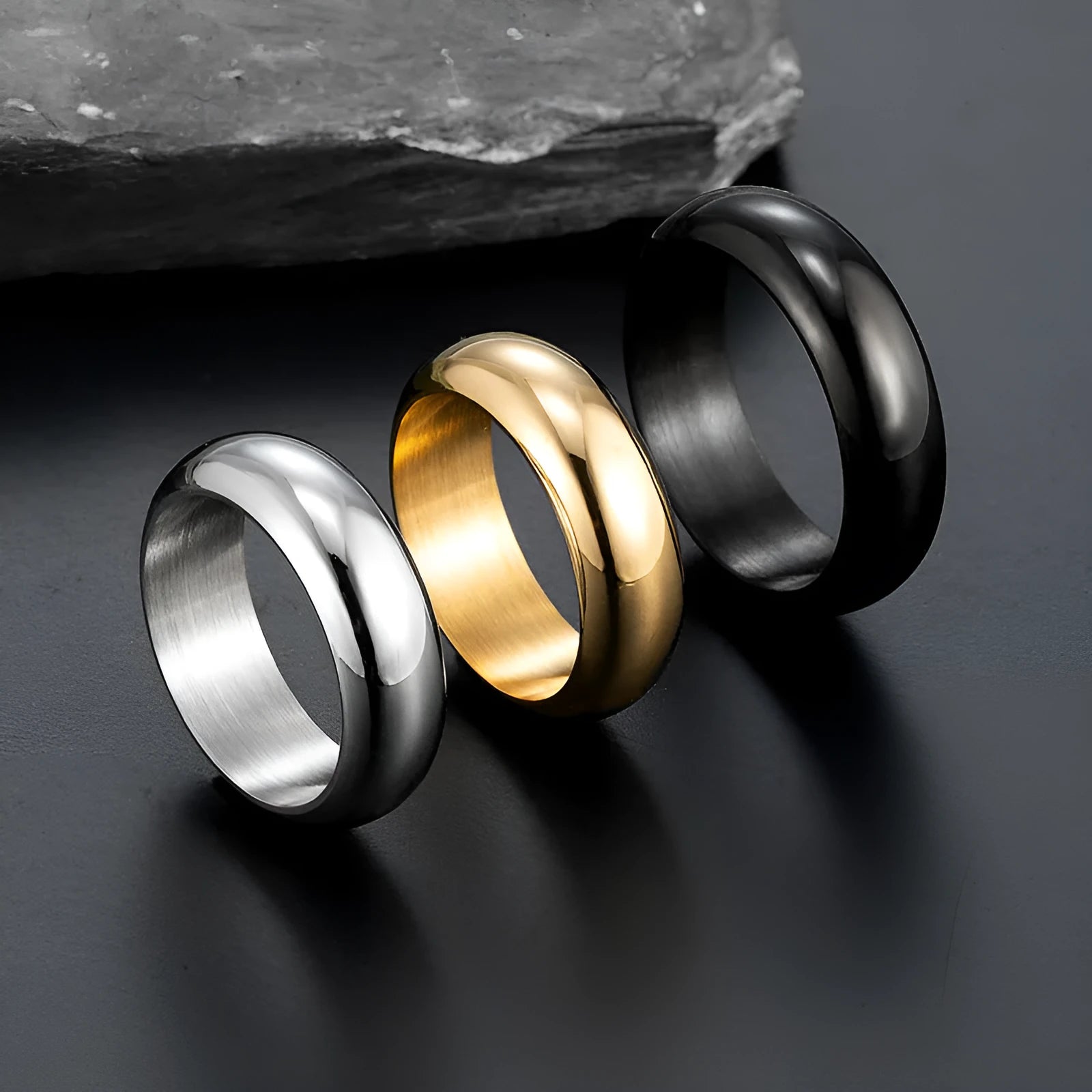 Glossy electroplated titanium steel ring in gold, black, and steel colour options on a grey background