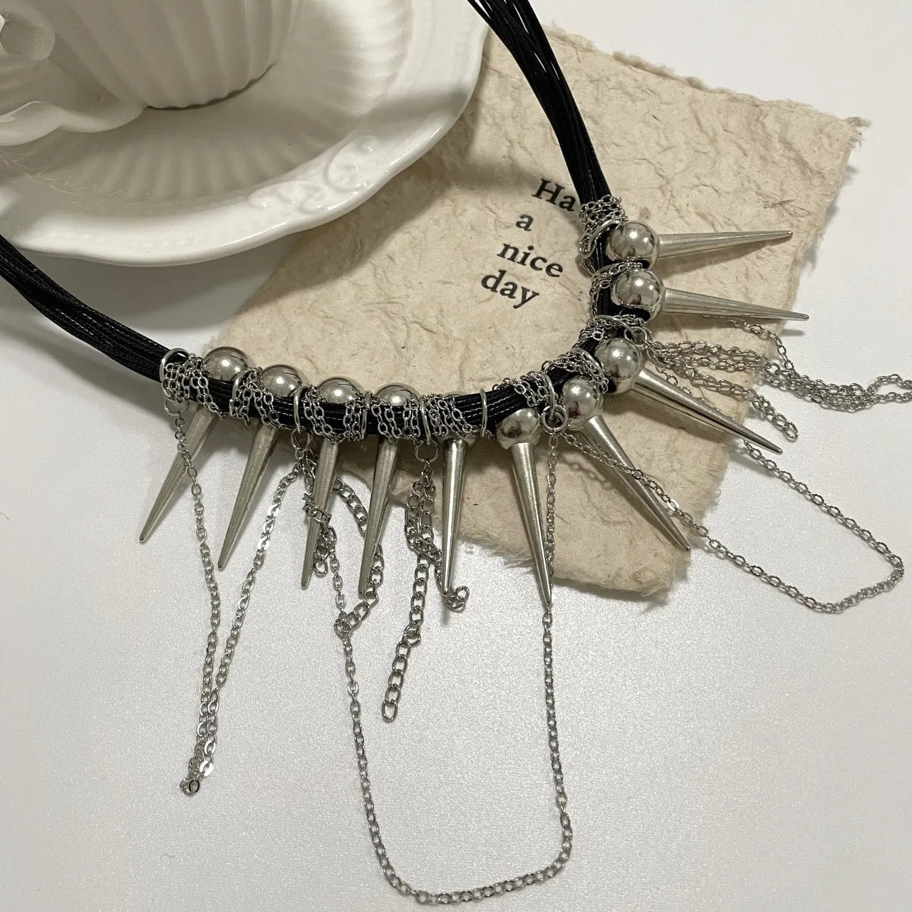Leather necklace with winding tassel, round beads, and metallic rivet details in a picture colour.