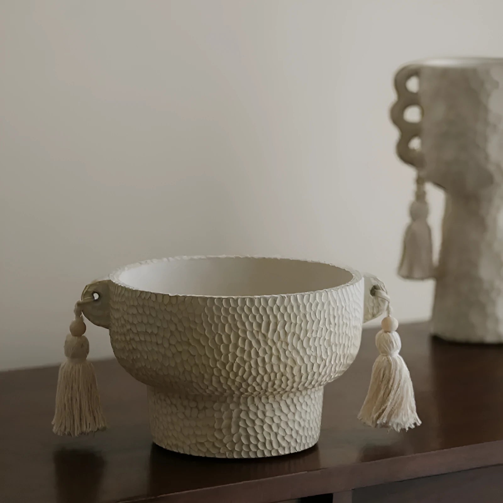 Ceramic binaural planter pot with decorative tassel flower motif on a white background.