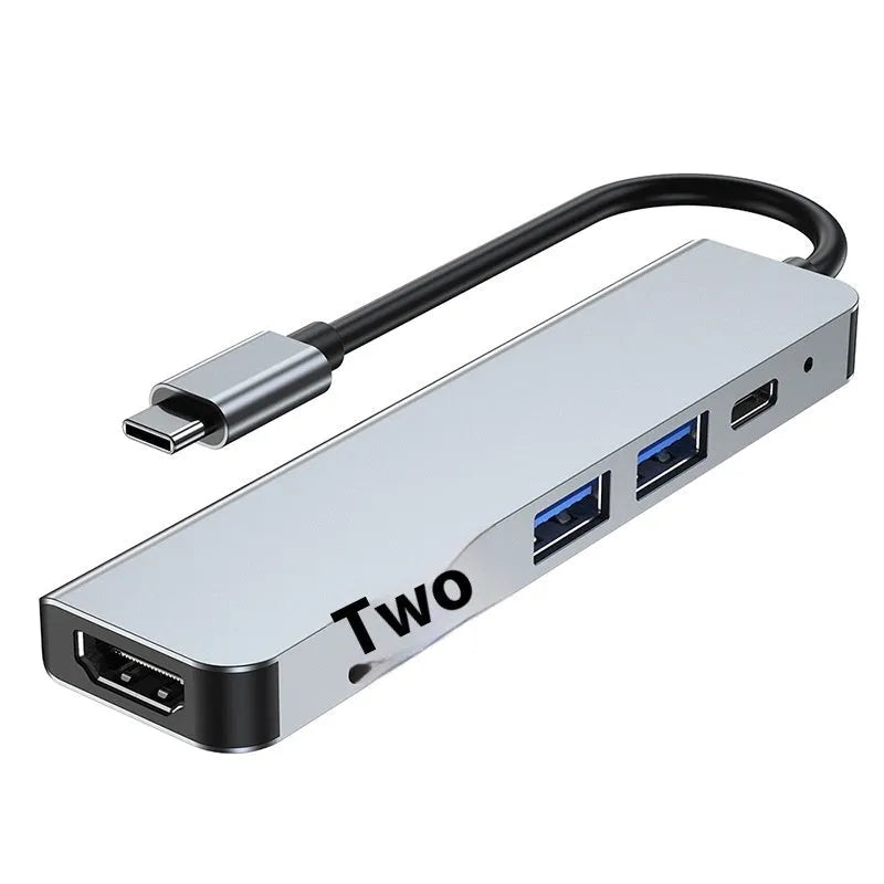 Compact silver USB-C expansion dock for laptops with multiple ports including HDMI and USB-A.