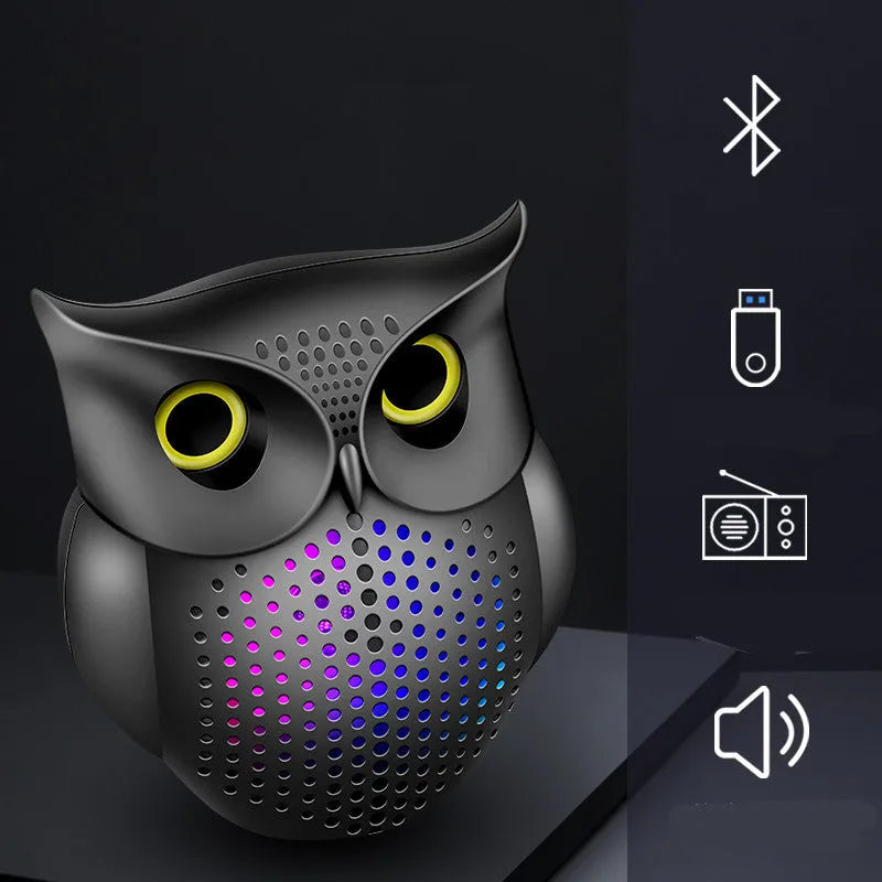 Black plastic owl-shaped portable Bluetooth speaker on a table.