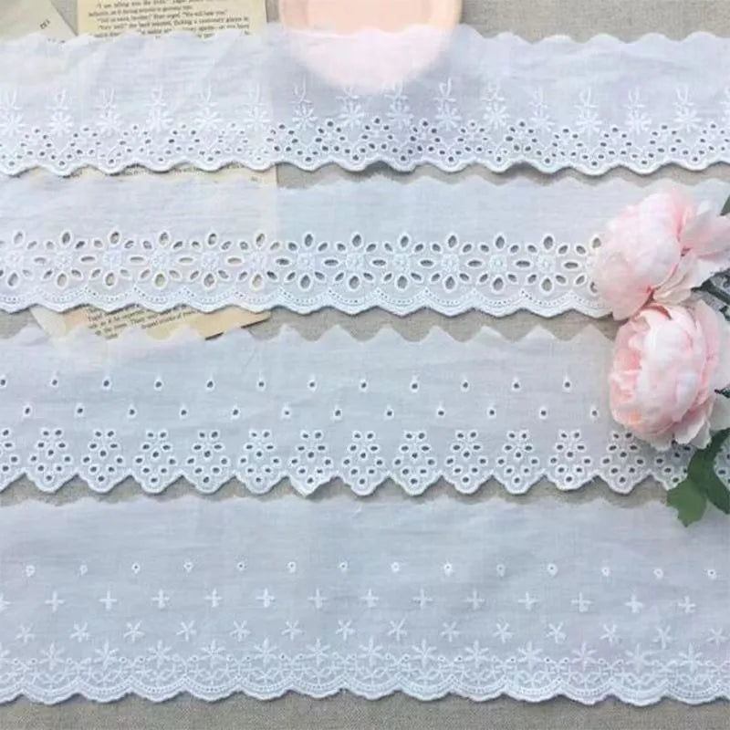 Reel of white embroidered cotton lace trim with a cutout design, showing four different width styles for DIY sewing.