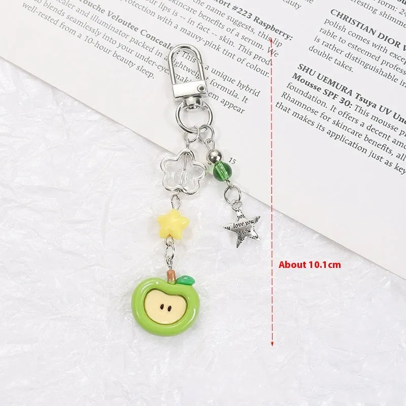 Red and green fruit-themed plastic mobile phone charm and keychain on a white background.