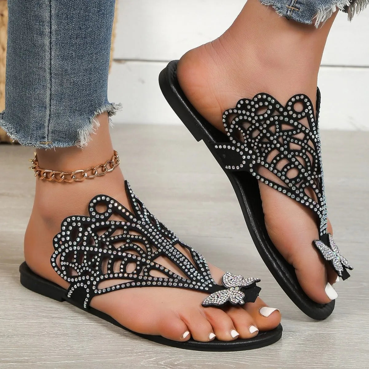 Women's black slip-on sandals with flip-toe design, rhinestone detail on the upper, and a flat rubber sole.