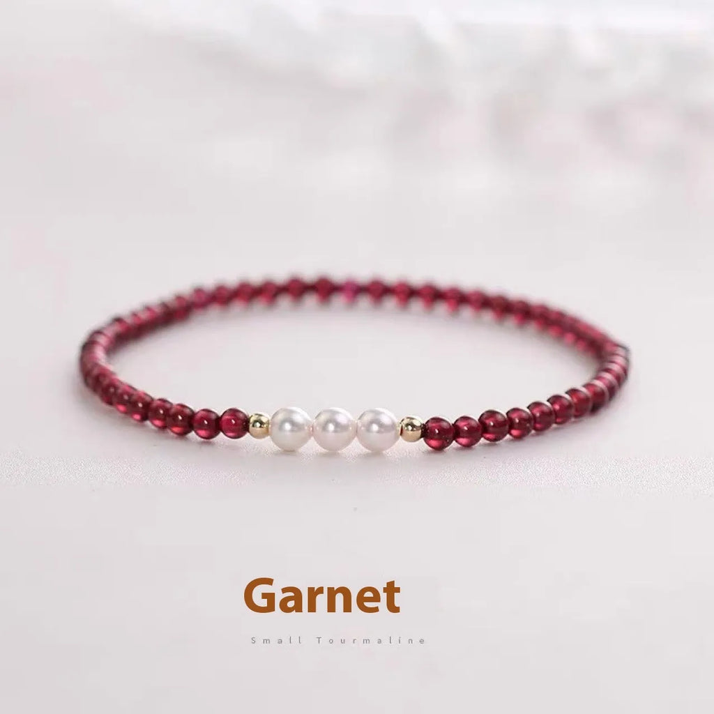 Close-up of a women's adjustable crystal bracelet with red garnet and white artificial pearl beads.