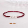 Close-up of a women's adjustable crystal bracelet with red garnet and white artificial pearl beads.