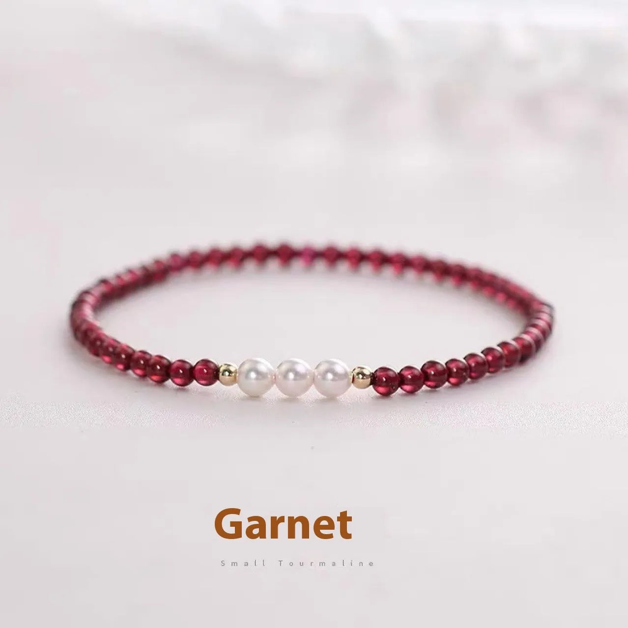 Close-up of a women's adjustable crystal bracelet with red garnet and white artificial pearl beads.