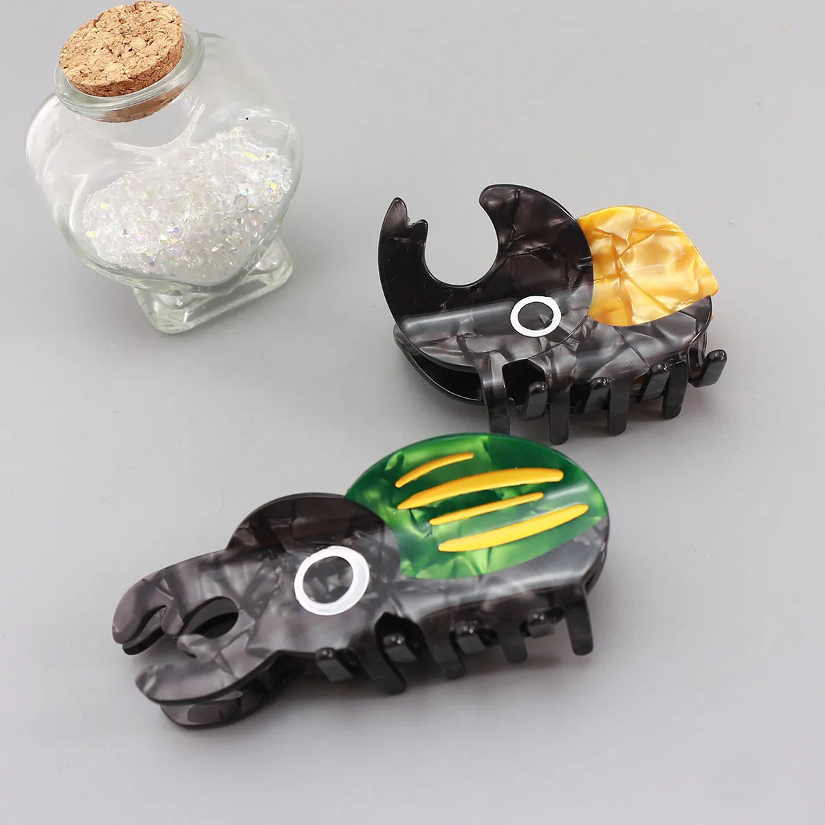 Handmade cartoon insect design hair grip in green beetle, orange beetle, or white caterpillar colour on cellulose acetate.