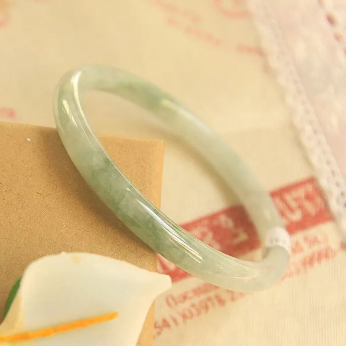 Green jade waxy geometric bracelet with Chinese design elements on wrist