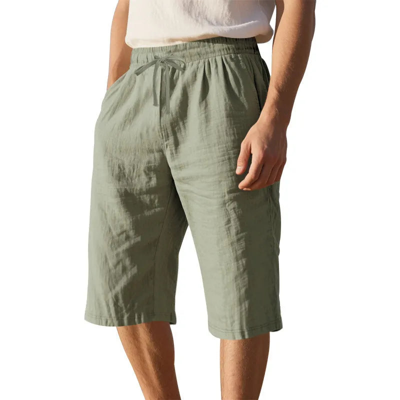 Men's solid colour linen shorts in a loose, cropped style on a drawstring waist.