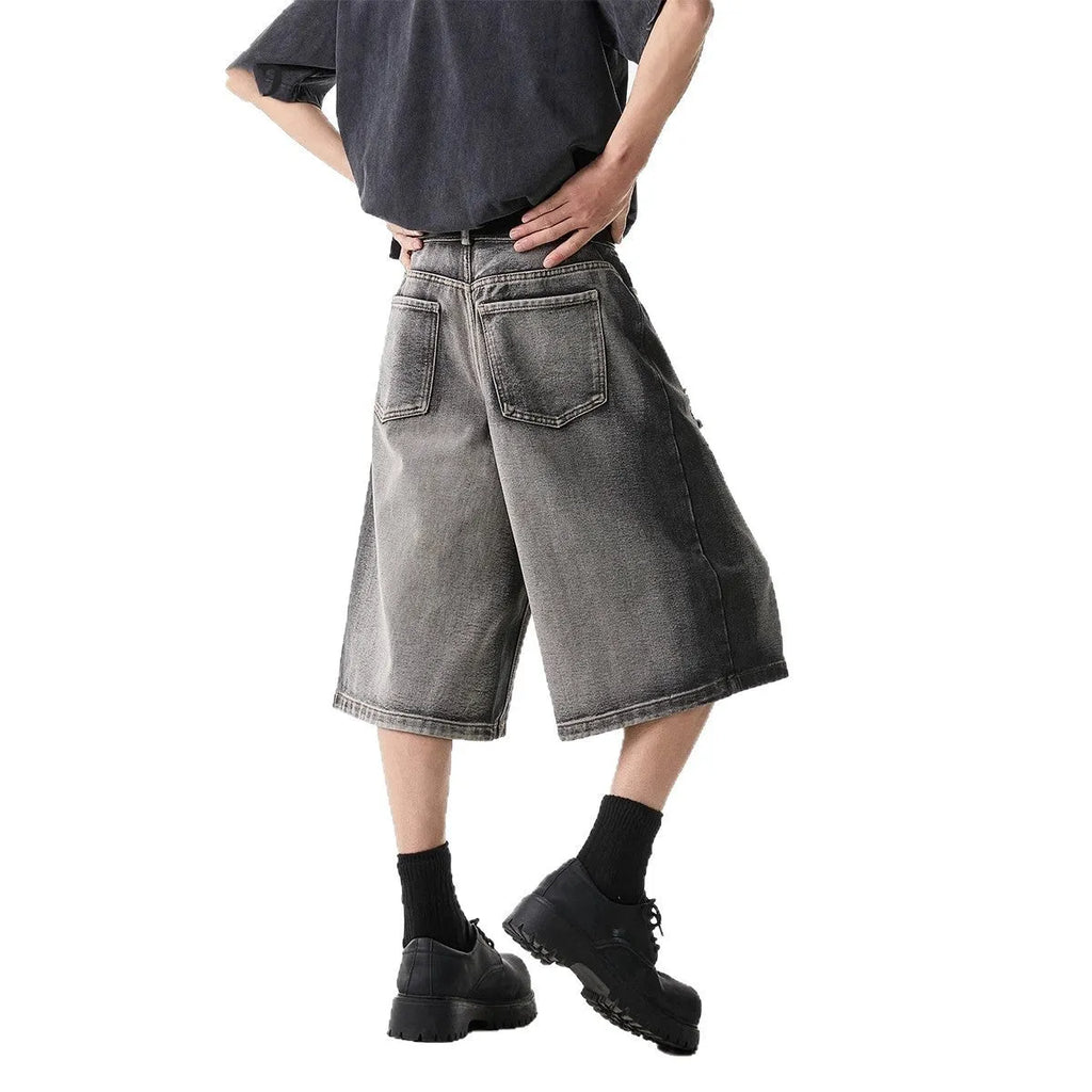 Grey denim shorts with washed finish and hole details, loose fit cropped length