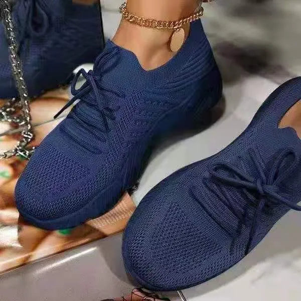 Women's white thick-sole dad sneakers on a plain background, showing the chunky sports shoe design.