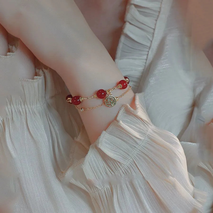 Close-up of a double-layer women's bracelet with a red agate blessing card and a red horse charm on an alloy band.