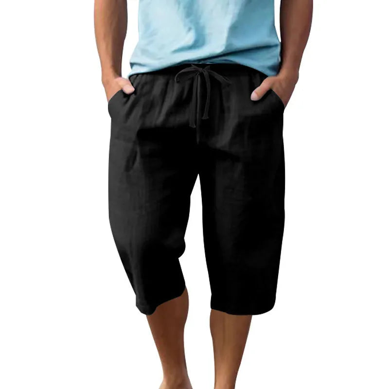 Men's solid colour linen shorts in a loose, cropped style on a drawstring waist.