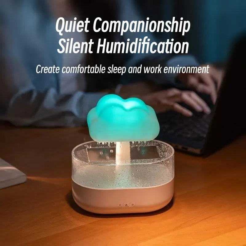 White cloud-shaped humidifier diffuser with multi-colour LED lights on a wooden surface.