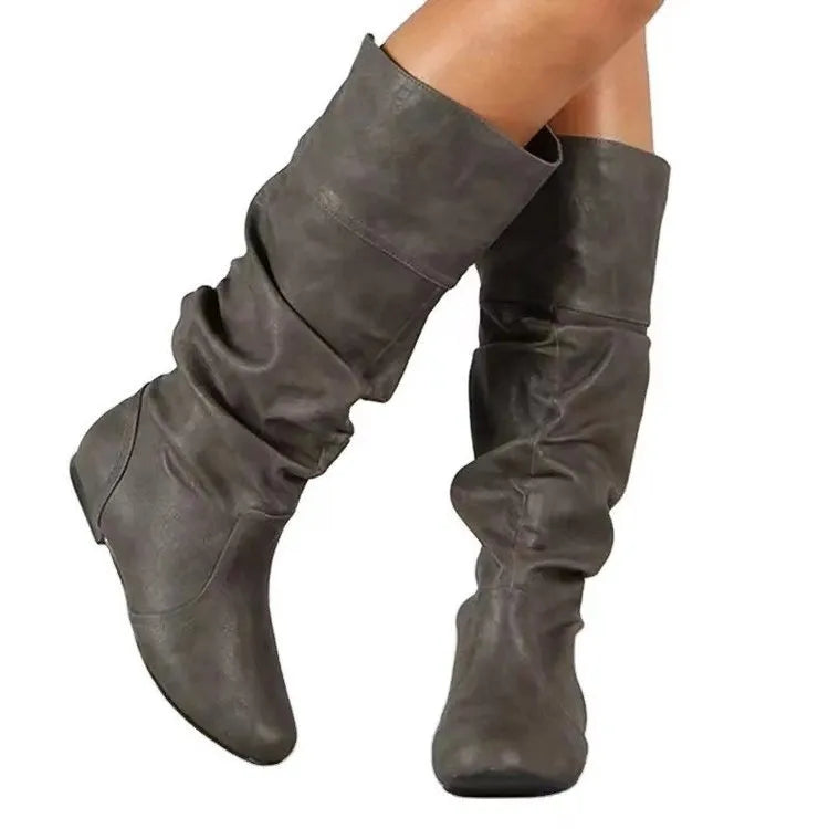 Women's flat heel slip-on boots in black with round toe and high cylinder length, showcasing non-slip rubber sole.