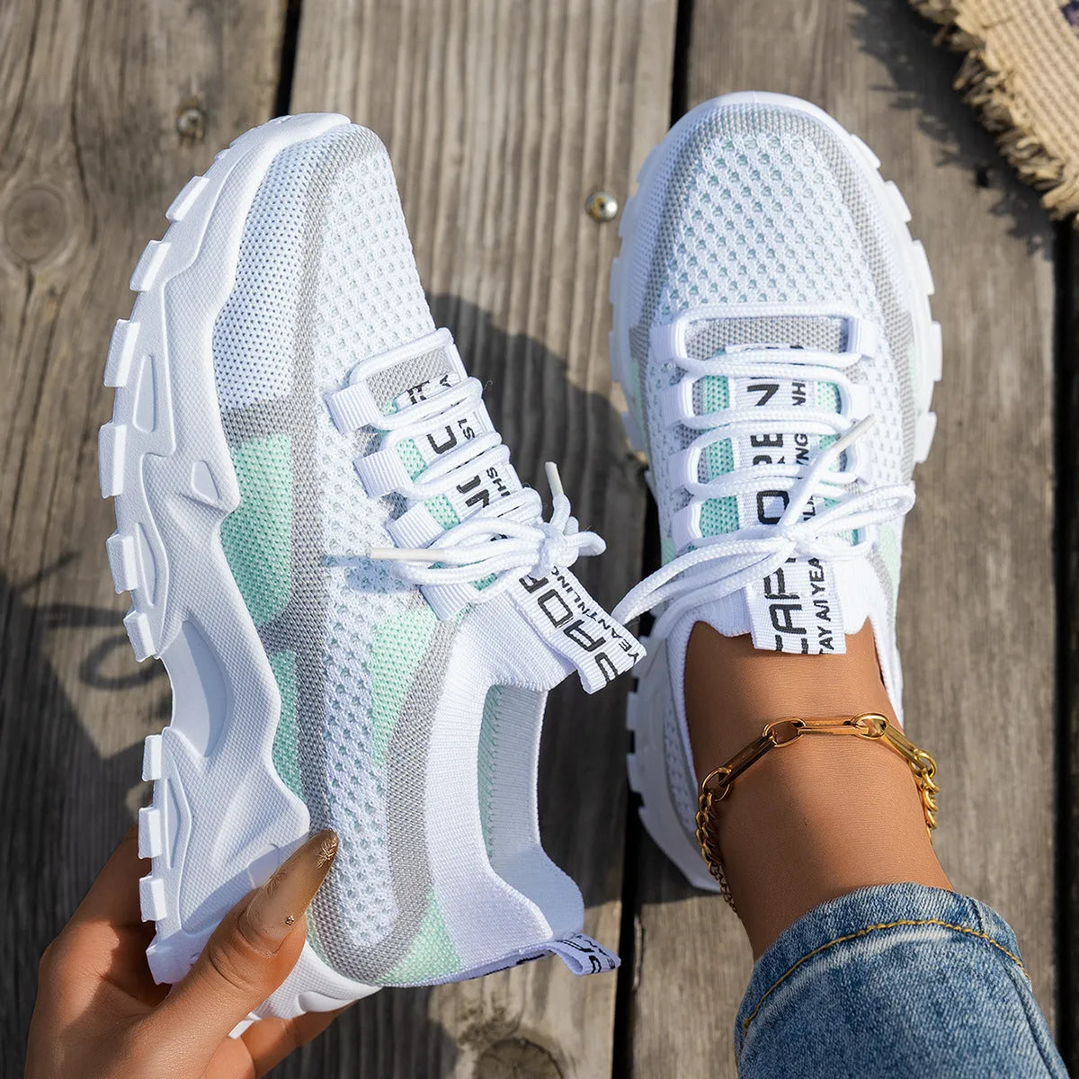 Women's Flyknit mesh sneakers in grey and white, showcasing the breathable upper and flat rubber sole.