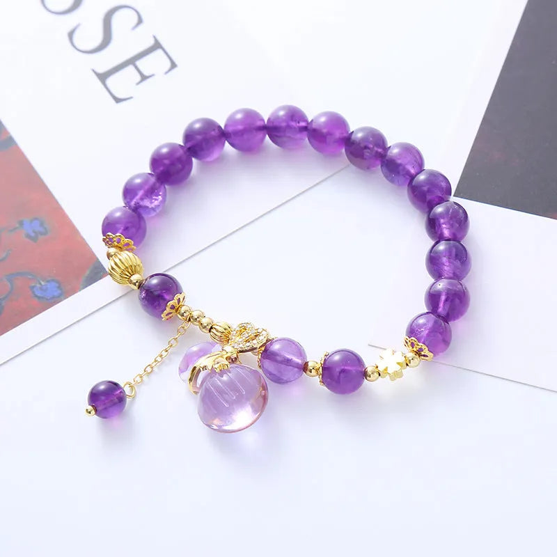 Purple amethyst bracelet with detailed money bag charm and peace buckle pendant on wrist