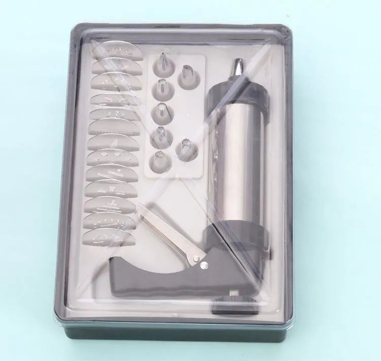 Stainless steel biscuit press gun with assorted cookie moulds and piping nozzles on a baking tray.