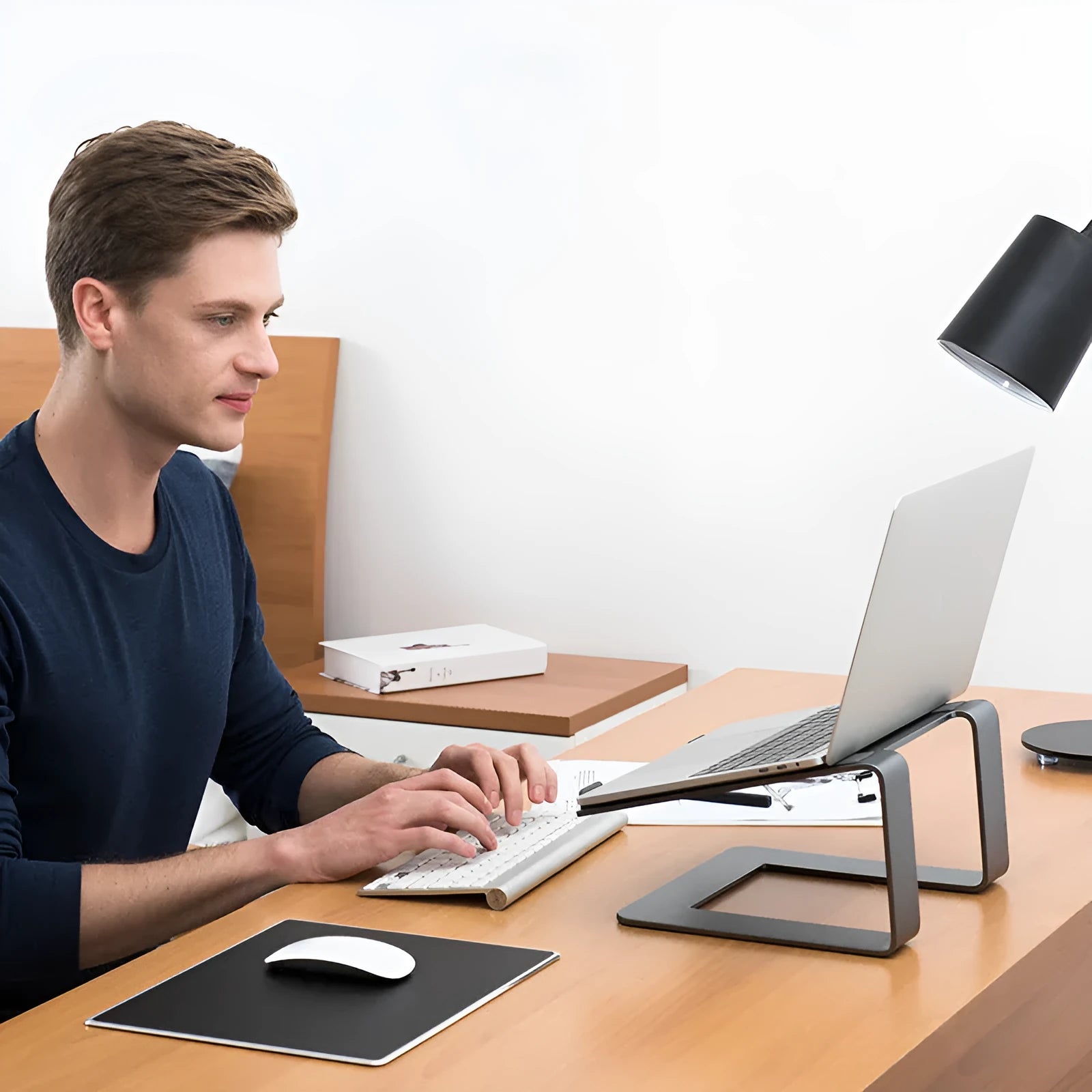 Aluminium alloy laptop stand in black or silver on a desk, showing its raised platform design.