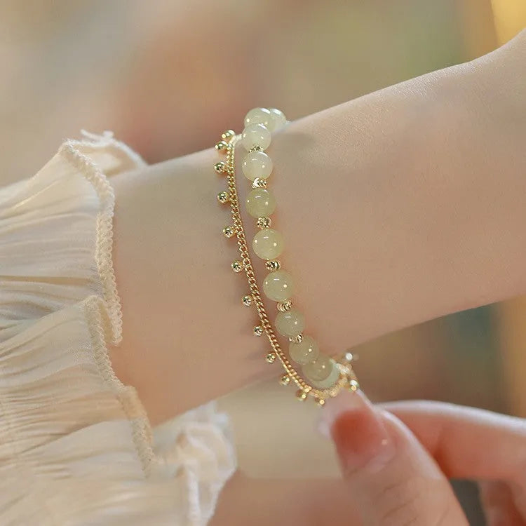 Natural Hetian Jade beaded bracelet with princess running motif on a wrist.