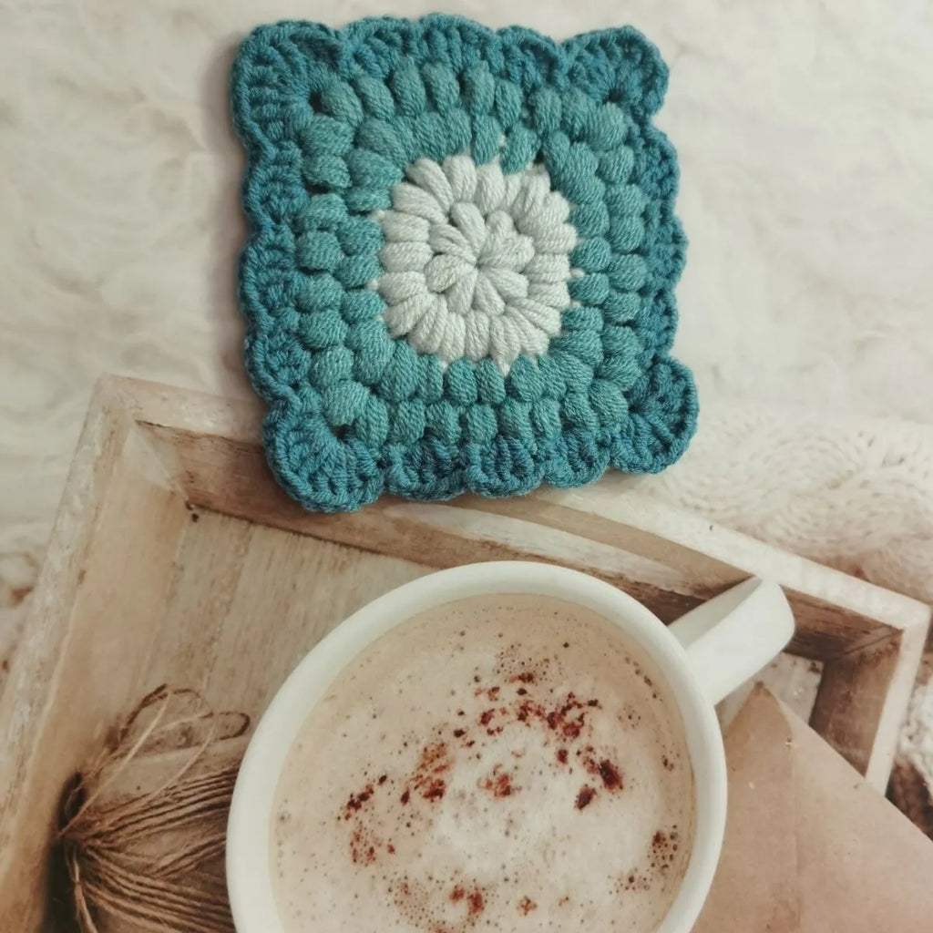 Crocheted grandmother lattice insulated cup placemat in wool, shown in one of four colours