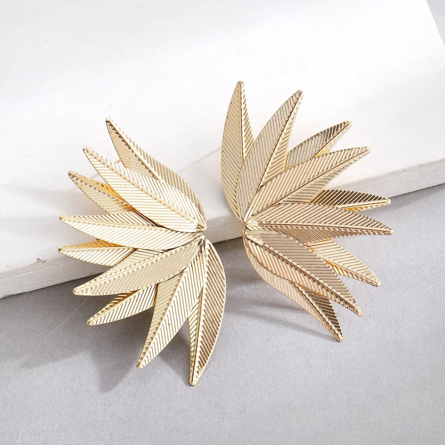 Gold and white alloy leaf-shaped stud earrings with botanical design