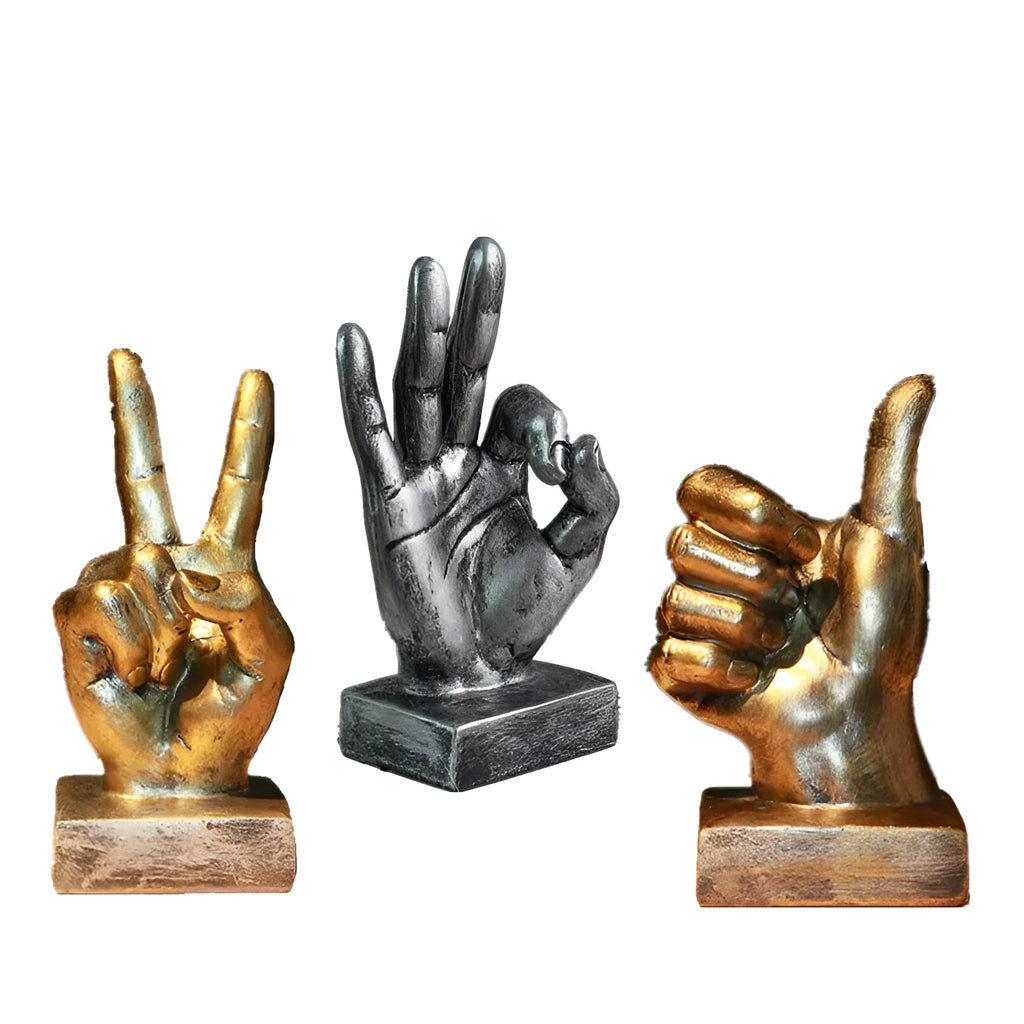 Bronze and silver resin hand gesture ornaments on a wooden desk, showing like, ok, and scissors hand signs.