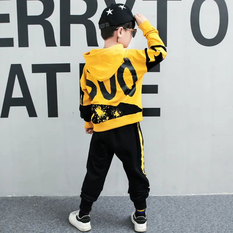 Boy's black and yellow hooded cotton sports suit trousers set on hanger, showing Korean style letter pattern.