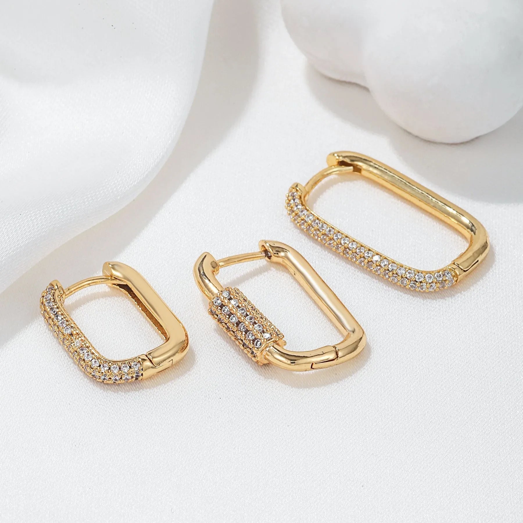 Three geometric copper ear clips with zircon detailing in ellipse and quadrilateral shapes on ear