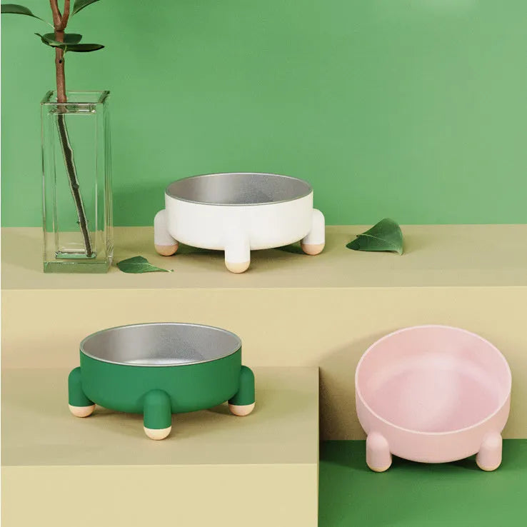 Green stainless steel pet bowl with non-slip base and high foot on a wooden floor.