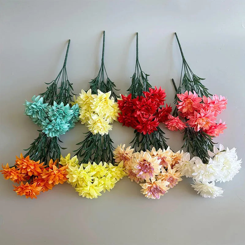 A fan-shaped display of silk dahlia, peony and rose flowers in a yellow colour on a wooden desktop.